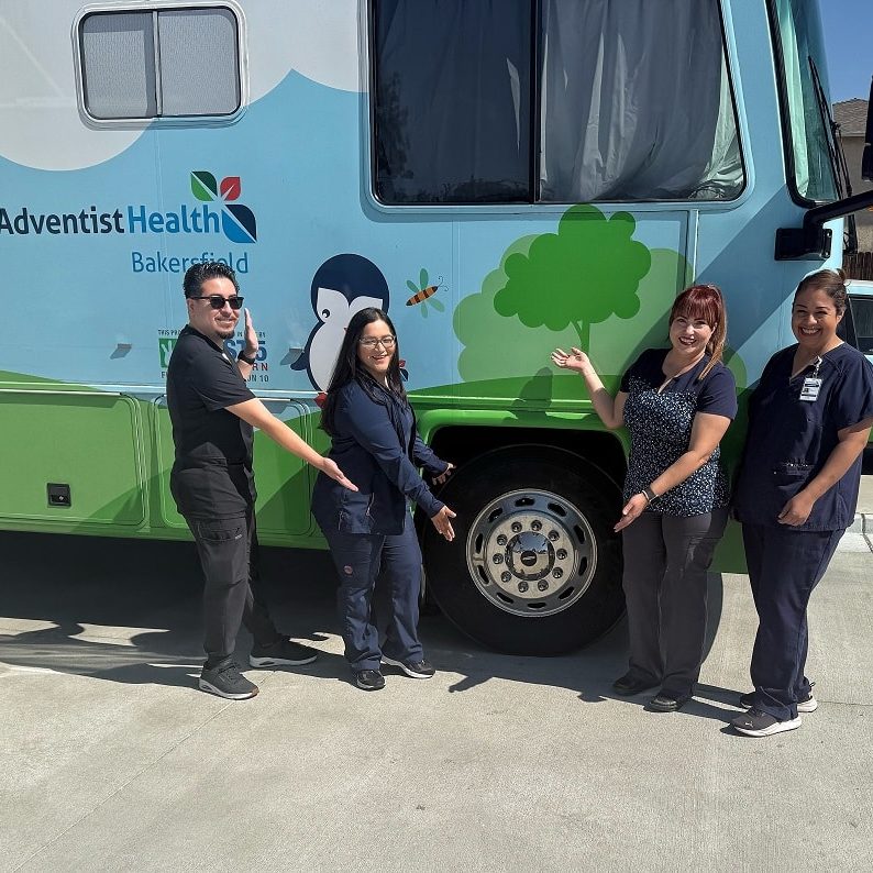 Adventist Health employees stand in front of mobile clinic.